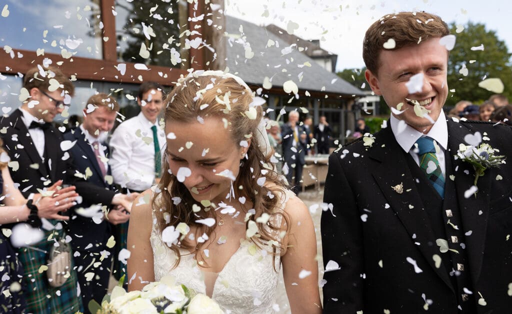 the bride and groom are covered with cofetti as they are welcomed by guests