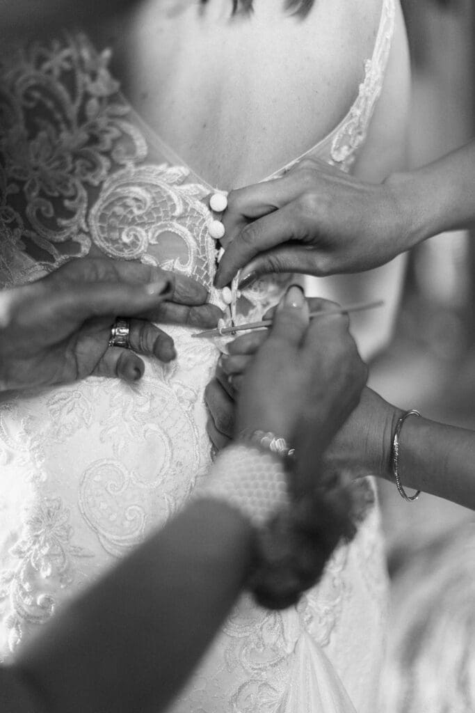 mother of the bride and the matron of honour help the bride in to her wedding dress