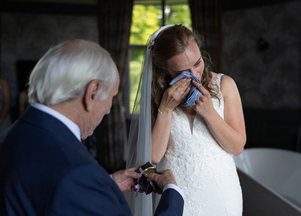 the bride cries as she gives her father a gift on her wedding day