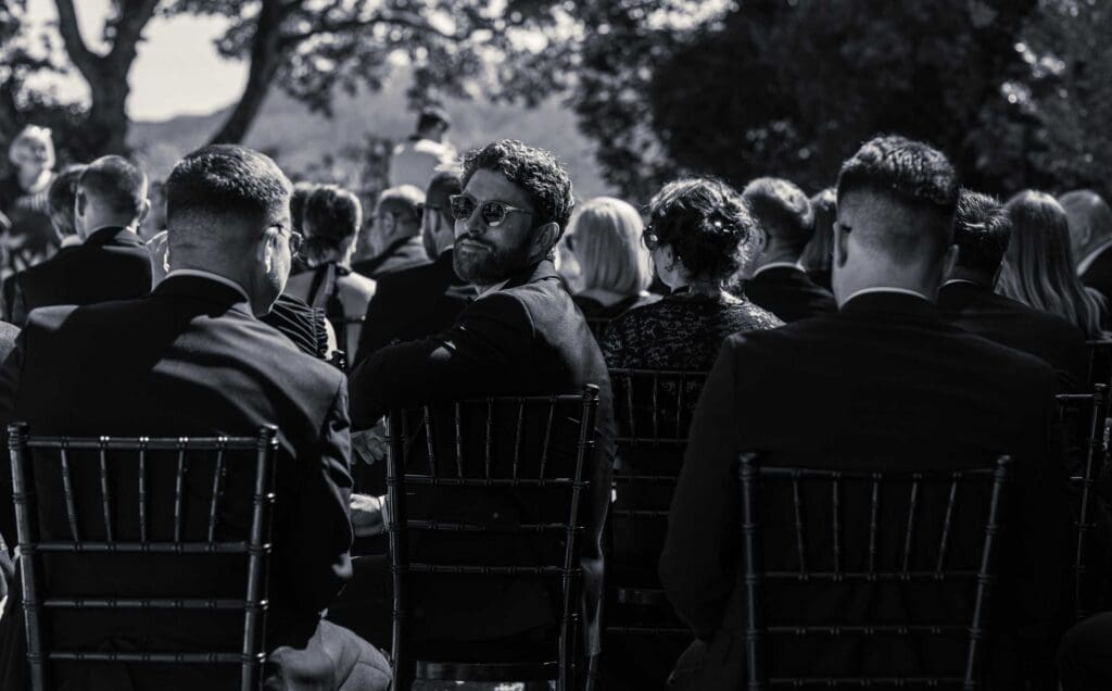 Second wedding photographer looking toward guests and groom