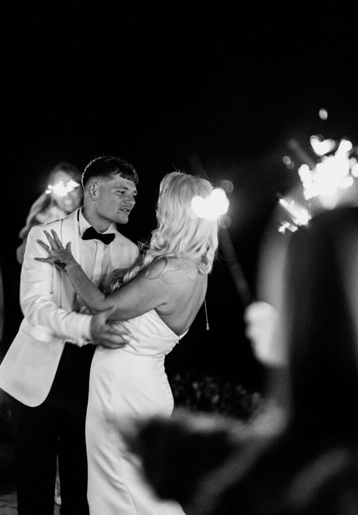 The bride and groom walk through a tunnel of sparklers their guests are holding