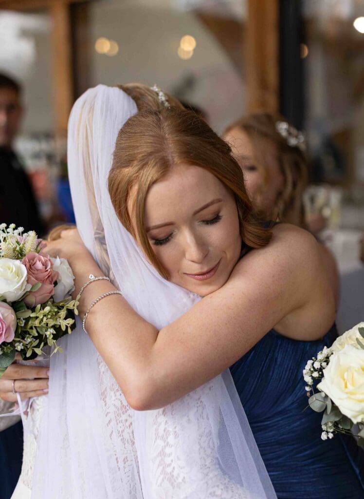 A bridesmaid hugs the bride after her wedding with so much love and emotion in her face