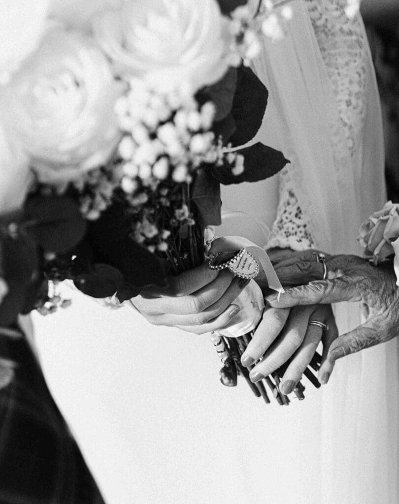 The bride is embraced by her gran as they touch hands on the brides flower bouquet