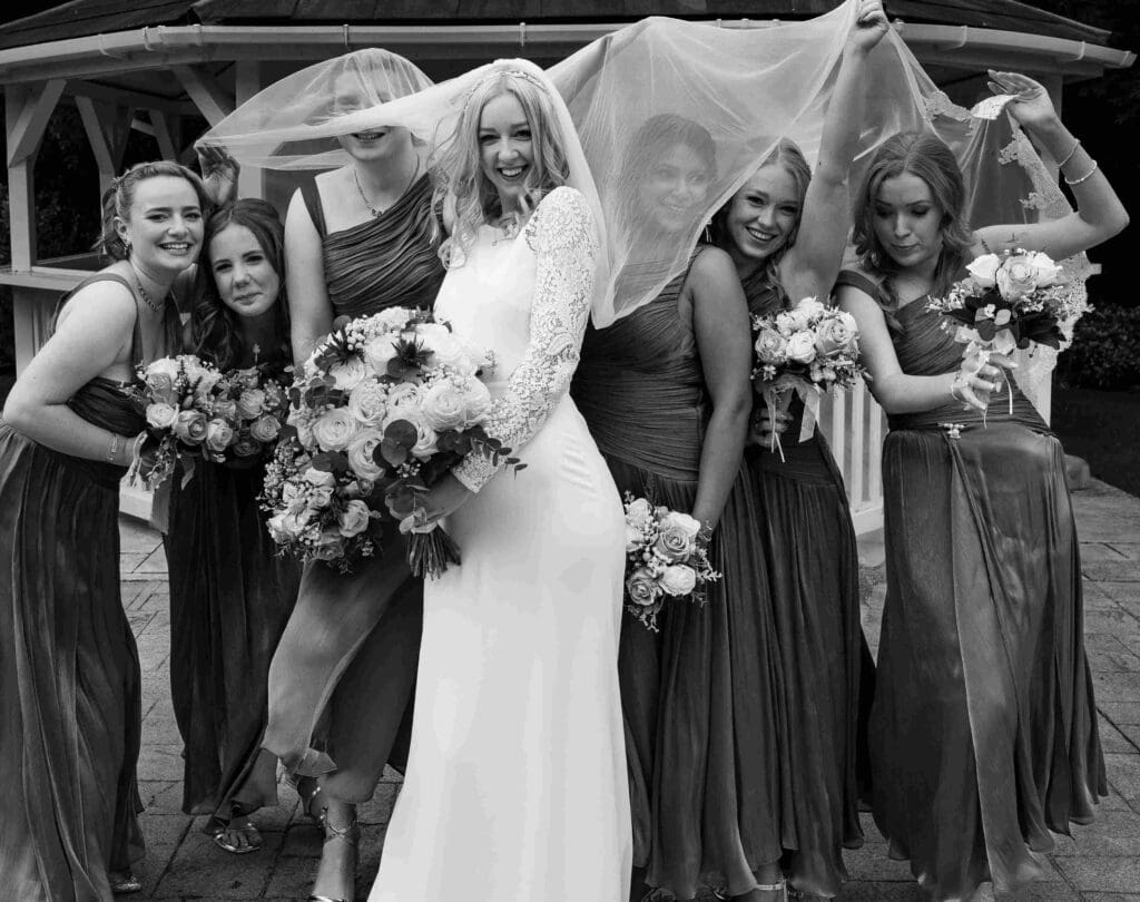 The bridal party have some fun under the brides veil.